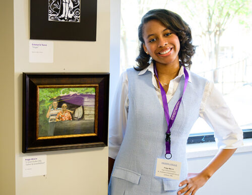 Young African-American woman smiling, standing next to her artwork that appears to be a watercolor featuring two men who are arm-in-arm, looking forward. 